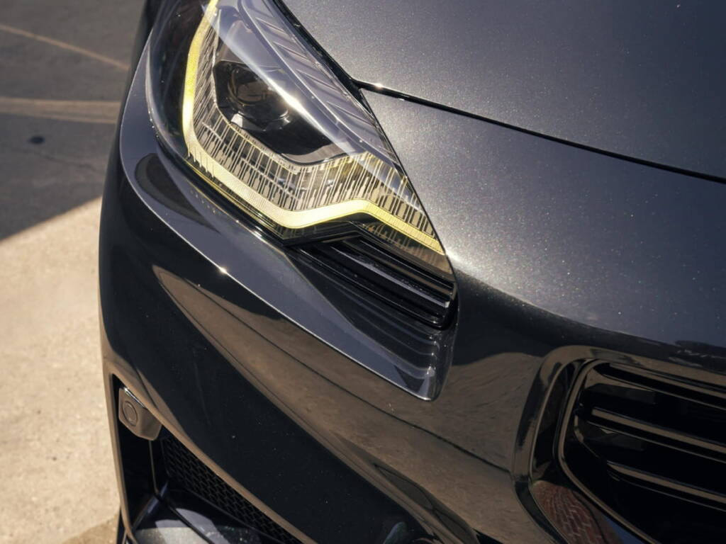 Close-up of a black vehicle headlight and front bumper showing a clean, protected paint finish.
