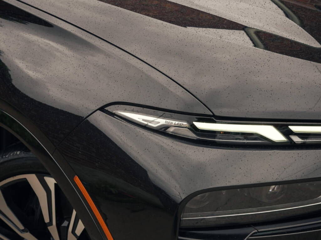 Close-up of a black BMW front end with water beading on the hood after paint protection or ceramic coating.