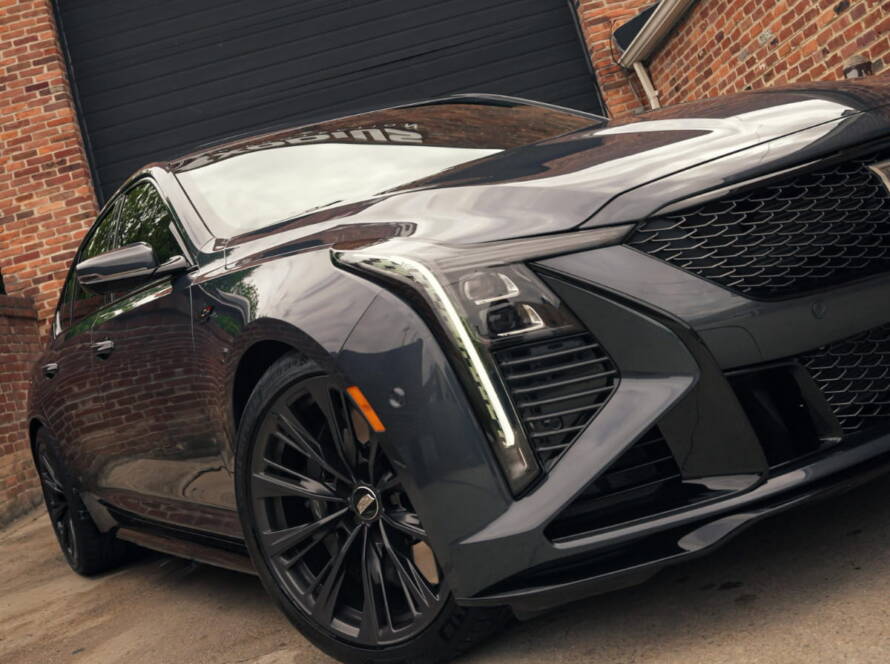 Black Cadillac SUV parked outside Exodius Auto Lab with a polished, glossy finish.