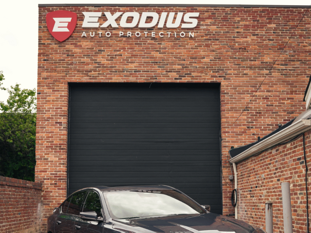 Exodius Auto Protection shop exterior with red brick facade black garage door and branded signage Alexandria Virginia