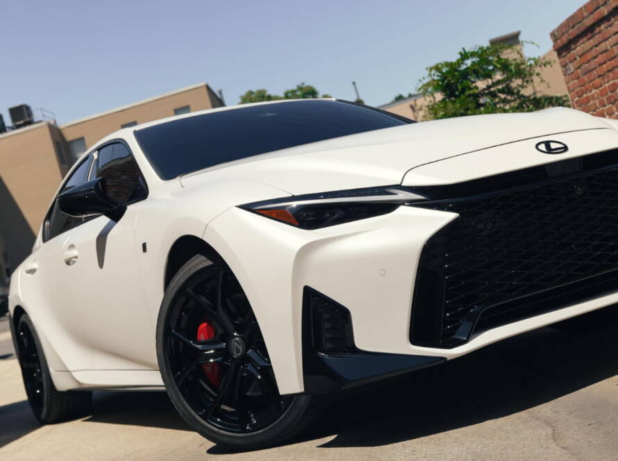 White Lexus sedan with black wheels parked outside after automotive detailing or paint protection service.